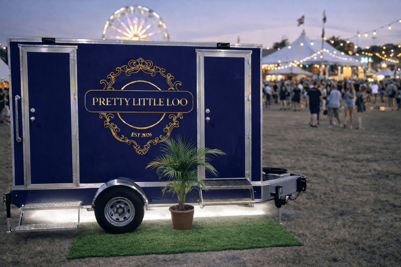 Pretty Little Loo trailer at an evening festival with string lights and ferris wheel